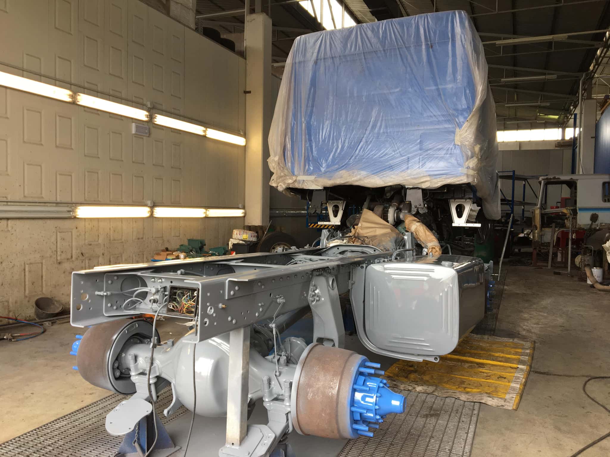 Telaio di un camion d'epoca riverniciato in officina, con la cabina protetta durante la lavorazione